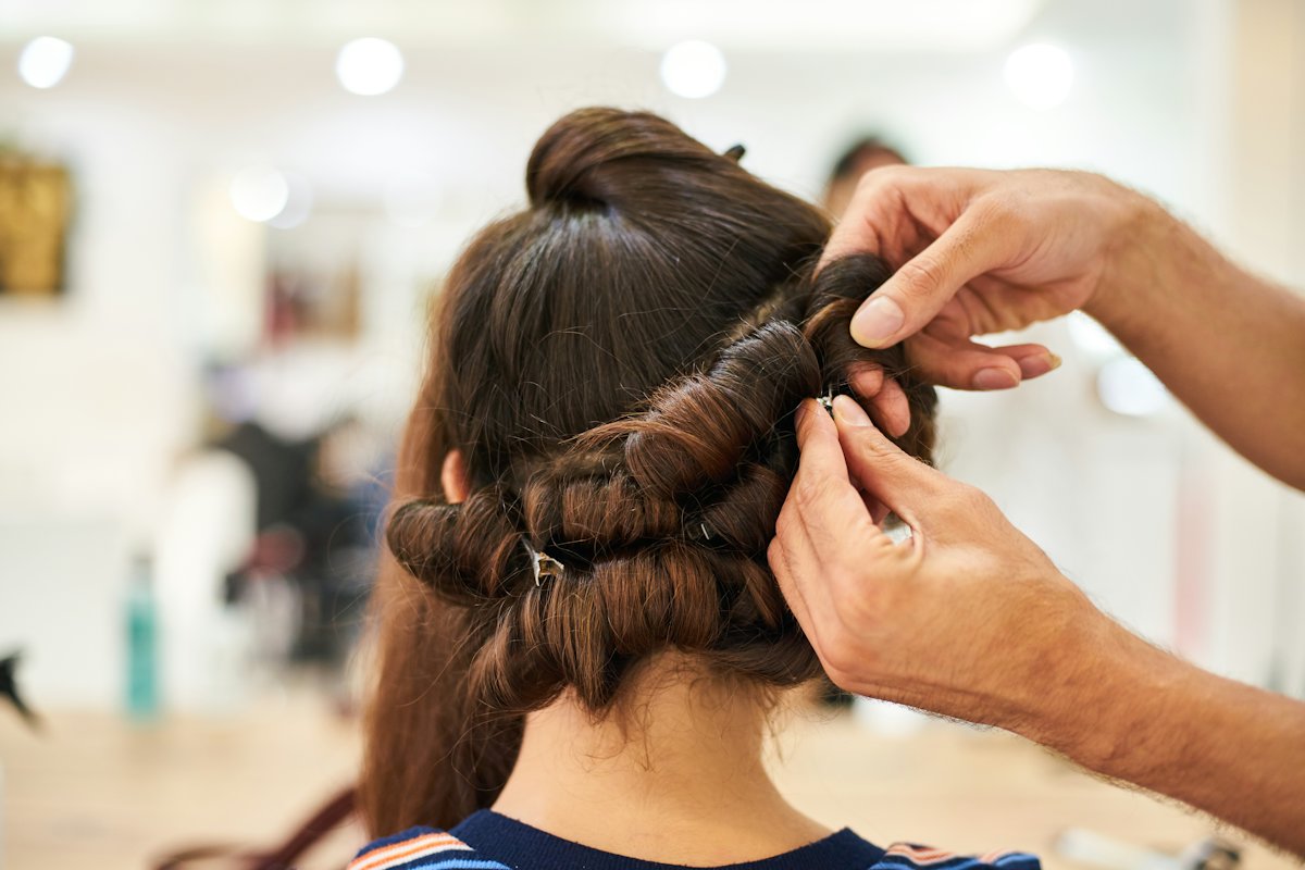 Coiffeuse réalisant un chignon bouclé