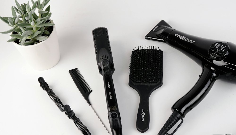 Sèche-cheveux, brosses et peignes sur fond blanc